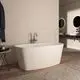 Freistehende Badewanne in Weiß von Ideal Standard, Platzierung auf Holzboden, mit Wasserhahn und Wandspiegel in modernem Badezimmer-Design.